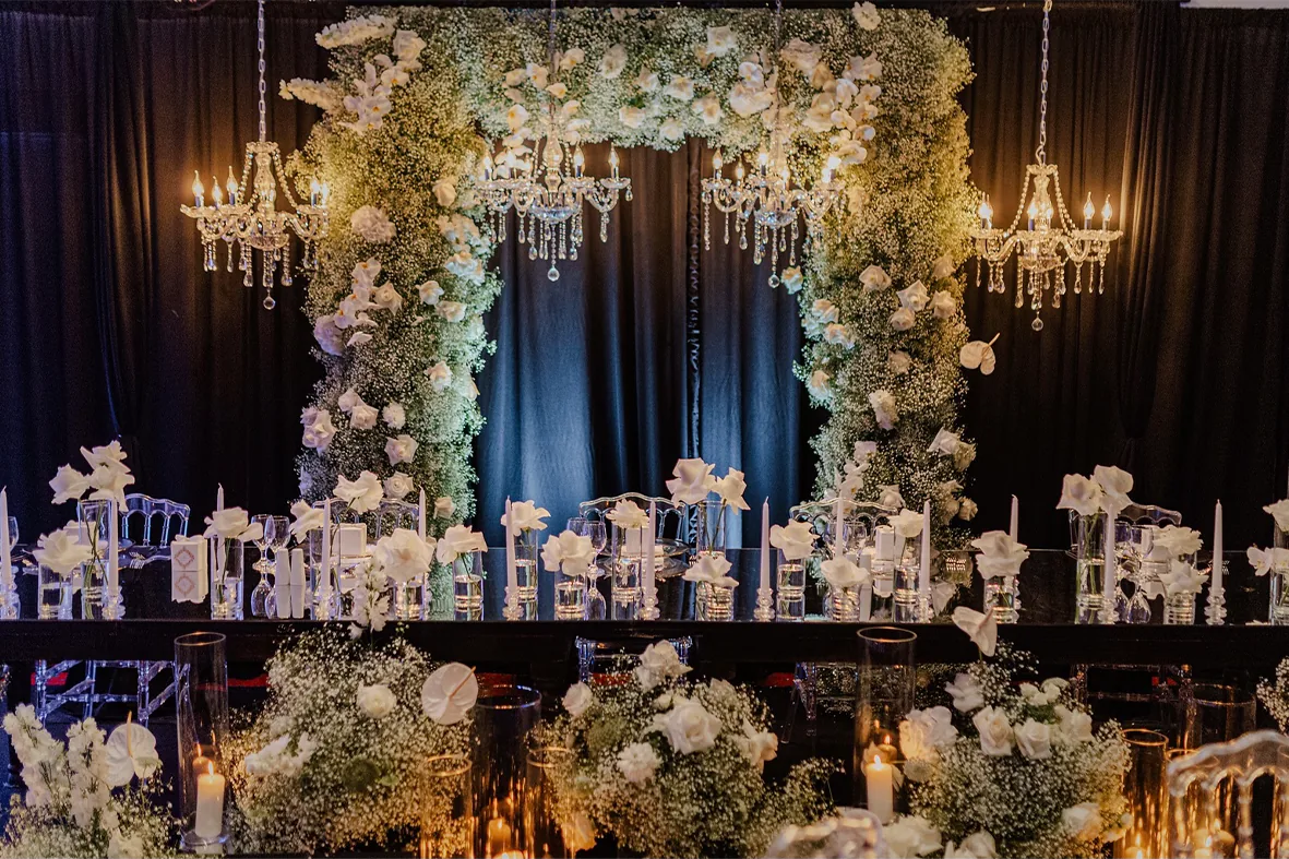 Reception room with white blossoms, chandeliers and a wedding cake